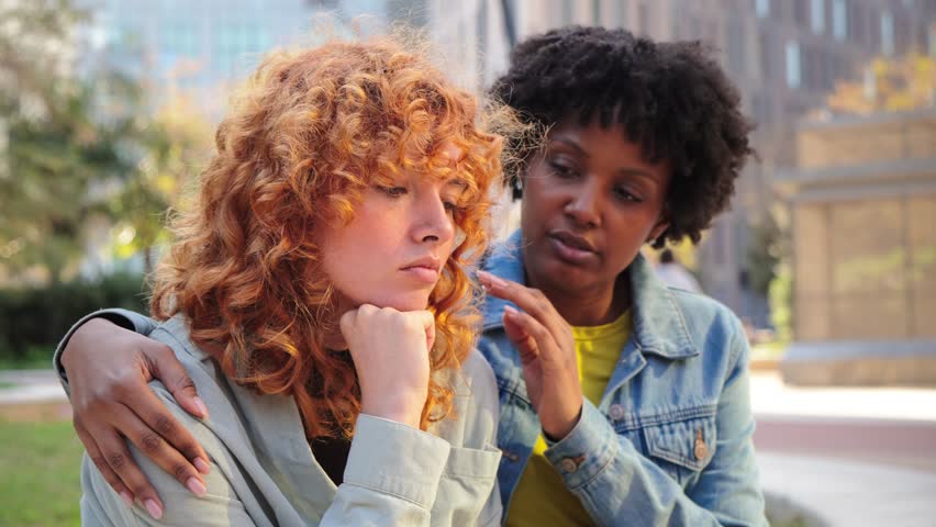 Two women engage in a supportive moment where one friend offers comfort and empathy to another experiencing emotional distress and sadness, showcasing the importance of friendship and support.