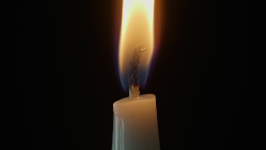 Wind shaking candle flame in blackness closeup. Wax taper fire trembling on air inside dark empty chamber isolated. Memory hope meditation silence spiritual energy symbol. Peaceful atmosphere concept