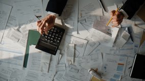 Accountant calculating corporate budget planning money profit at table top view. Business man hands holding documents analyzing expenses doing work using calculator over paper bills invoices indoors - Powered by Shutterstock - Get 15% off with code: PIKWIZARD15