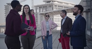 A diverse group of business professionals collaborates on a rooftop terrace, overlooking the cityscape. Their discussion involves strategic planning and project analysis. - Powered by Shutterstock - Get 15% off with code: PIKWIZARD15