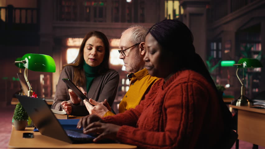 Focused students taking notes from academic library resources and reviewing archived materials in a study area, showing the dedication of mature education and knowledge building. Camera B. - Powered by Shutterstock - Get 15% off with code: PIKWIZARD15