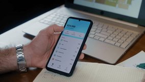 A professional man makes a digital money transfer on his phone while working, - Powered by Shutterstock - Get 15% off with code: PIKWIZARD15