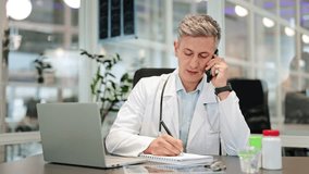 Focused medical professional takes important notes while on a phone call consultation at an office desk. Doctor is diligently working, providing medical advice and showing serious concentration. - Powered by Shutterstock - Get 15% off with code: PIKWIZARD15