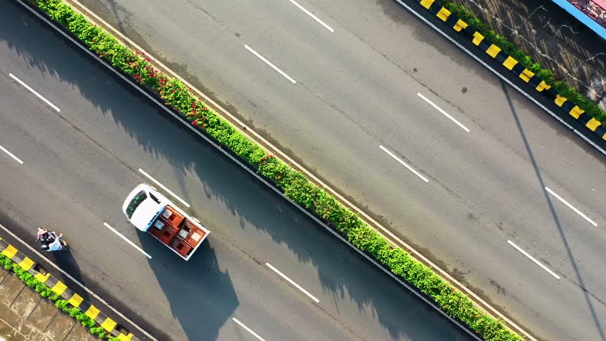 Smooth moving traffic on a clean expressway with dividing greens in center.