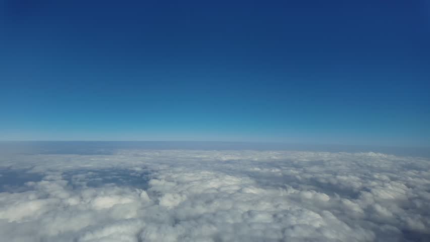 An immersive POV flying at hypersonic speed. Aerial footage taken from a jet cockpit while flying over a layer of cottony clouds, and under a blue sky. 4K