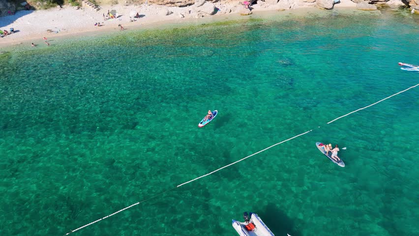 Beautiful Young Woman in Bikini Stand Up Paddling Sup Surfing in Stara Baska Skrila Beach Krk Island, Croatia. Mediterranean Summer. Aerial Shot From Above. Blue Sea the Rocks Mountains and Coastline