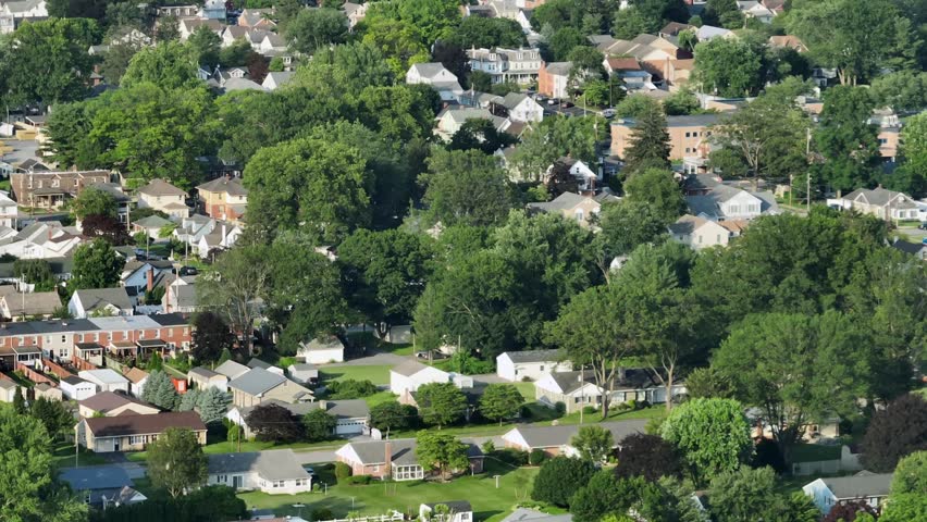 Townhouses and row of homes between green trees in idyllic neighborhood. Aerial lateral zoom shot. Quiet and historic city neighborhood in summer season. Wide shot.