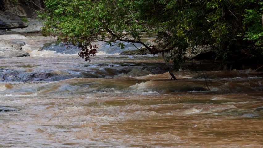 The nature of the waterfall in the forest that flows strongly during the rainy season. Strong current in the river, waters turned muddy after heavy rains in autumn.