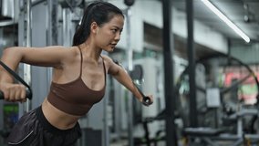 Determined sportswoman exercising upper body muscles using cable machine in modern fitness center - Powered by Shutterstock - Get 15% off with code: PIKWIZARD15