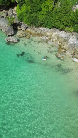 Aerial view of mid adult man with surfboard swimming at the shallow of Indian Ocean.Nusa Dua.Bali.Indonesia. High quality 4k footage