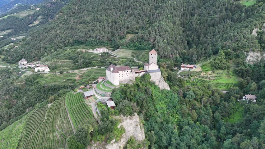 Orbit flight around Tyrol Castle in the mountains of Tirol (Dorf Tirol) with vineyard panorama in South Tyrol, Italy