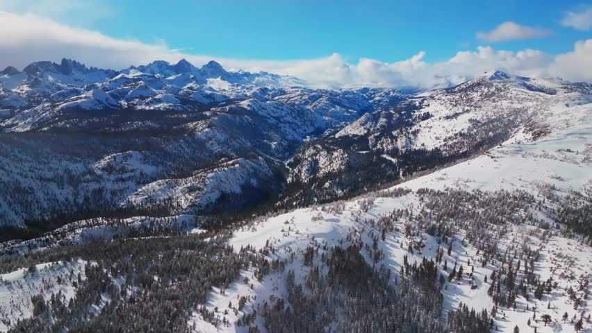 Mammoth Mountain ski resort California Hemlocks panorama Winter Spring Minarets Summit vista Ritter Sierra Nevada range sunny blue sky snowy clouds over jagged peaks Inyo Sierras National Forest pan