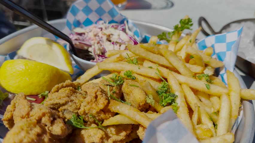 Delicious crunchy fried oyster platter and ahi poke nachos, closeup tracking shot. Hand is seen grabbing a french fry from a platter.