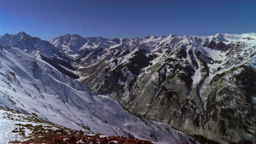 Winter Maroon Bells Capital Peak Wilderness jagged peaks Aspen Highlands ski resort bowl backcountry high alpine steep terrain Colorado landscape blue sky deep snow sunny panorama pan left
