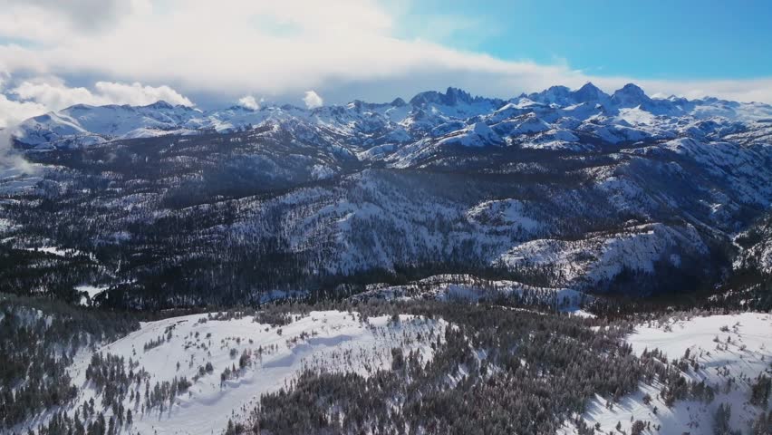 Minarets jagged towering peaks Summit Vista panoramic landscape aerial drone winter Mammoth Mountain Ski Resort California Inyo National Forest the Hemlocks sunny blue sky cloudy parallax circle left
