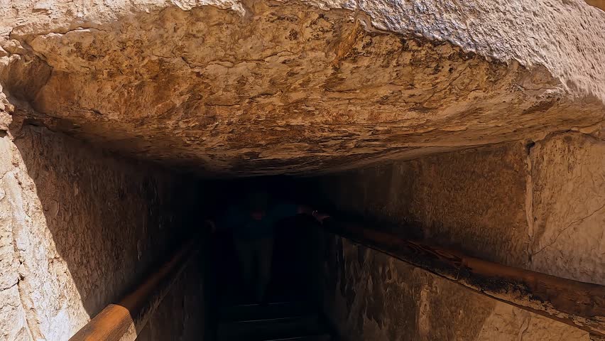Female tourist emerges from small passage to underground Egyptian tomb