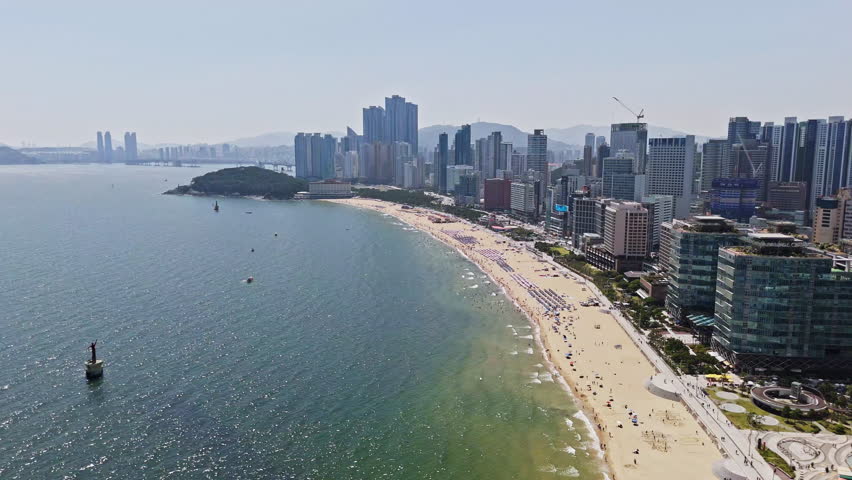 Drone flying along the famous Haeundae beach, sunny day in Busan, South Korea