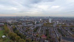 Cinematic aerial footage of London’s urban park with a running track, sports field and pool in the foreground, transitioning to terraced rooftops and the iconic skyline under dawn skies. - Powered by Shutterstock - Get 15% off with code: PIKWIZARD15