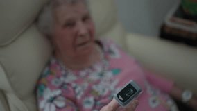 Closeup of an oximeter displaying oxygen levels on the finger of a senior woman in a care facility, highlighting health monitoring in aged care. - Powered by Shutterstock - Get 15% off with code: PIKWIZARD15