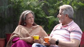 Happy Indian senior couple drinking tea or coffee in colorful mugs sitting at garden. - Powered by Shutterstock - Get 15% off with code: PIKWIZARD15