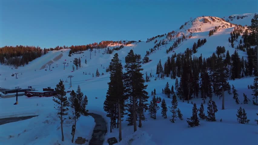 Sunset blue hour Mammoth Mountain ski resort spring winter California aerial drone Unbound Terrain Parks panorama landscape ski snowboard groomed trail runs chairlift gondola upwards motion