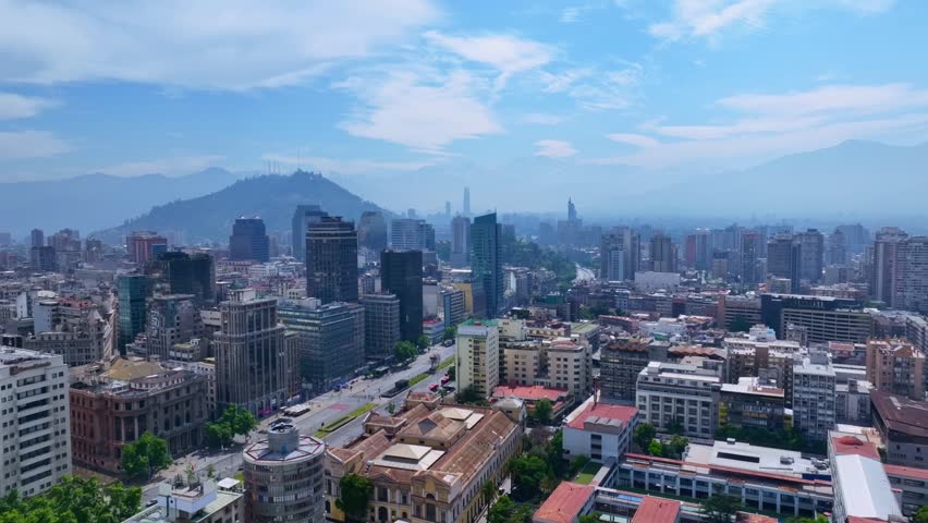 Aerial View of Santiago City With Modern and Historic Buildings, Tree-Lined Avenue, and Mountains in the Background