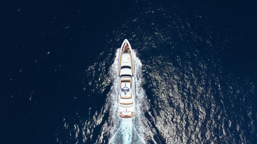 Aerial overhead tracking of a luxury yacht cruising over blue ocean