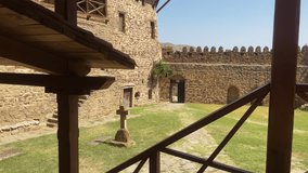 Camera tilt near a lone cross next to monastery’s stone walls, with wild grasses swaying under a desert sun. Ideal for pilgrimage or Georgian heritage content. - Powered by Shutterstock - Get 15% off with code: PIKWIZARD15