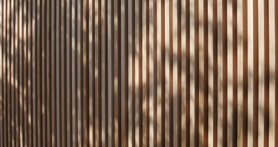 Wooden slats of alternating shades create a visually appealing pattern. The play of light and shadow adds depth and texture to the composition. nature, and modern aesthetics.