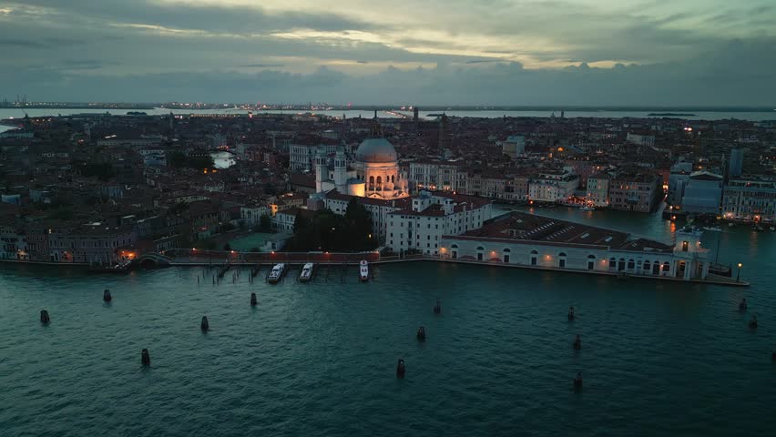 Aerial view Real time Footage top view of Basilica de Santa Maria Della Salute, flying higher see the city of Venice with crowded traffic by boat over the grand canal at twilight time, Italy