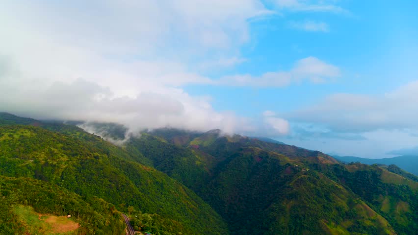 Serene and peaceful atmosphere of mountain peaks in the clouds. Green mountain landscape in summer. Natural scenery of hilly surface of mountain range. Bird's eye view of Caribbean morning nature.