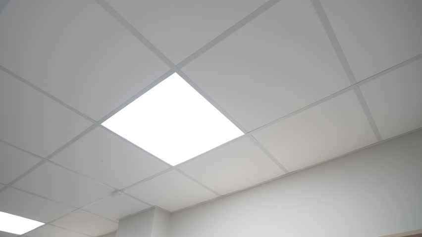 Glowing square led lamp on suspended ceiling in office low angle shot. Bright lighting equipment illuminates lobby of public building