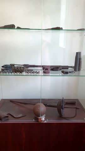 Museum exhibits lie behind glass, On the shelf lie ancient weapons from excavations, guns with traces of time