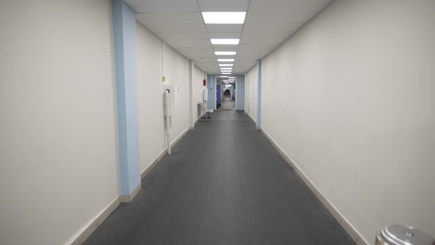 Empty corridor with doors and led lamps in modern hospital. Long hallway with clean walls inside clinic building. Office center interior