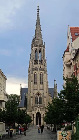 Katowice, Poland- 07.01.2025: majestic silhouette of a Neo-Gothic church rising above a charming street in Poland. The church, characterized by its tall spire, ornate detailing, and large clock faces
