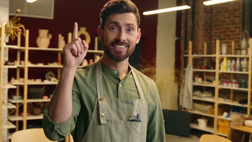 Happy creative smiling Caucasian guy man small business owner businessman potter craftsman crock male looking at camera thinking solution having brilliant idea eureka insight indoors workshop pottery