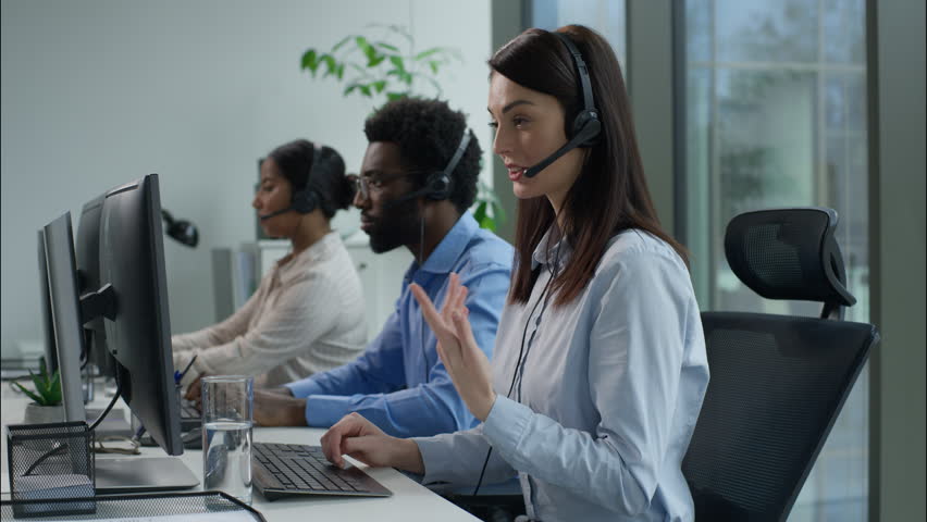 Helpline callcenter multiethnic business workers working online computer office customer service call center diverse smiling Caucasian Indian women African man in headset speak work pc helping client
