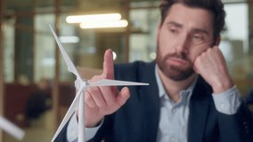 Upset frustrated Caucasian business man looking windmill thinking typing laptop at office businessman male guy engineer entrepreneur wind turbine working online computer pensive ecology green power - Powered by Shutterstock - Get 15% off with code: PIKWIZARD15
