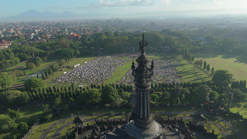 Eid al-Adha Prayer Gathering Bali.
Aerial view of a large gathering of Muslim people arranged in rows in an open field for Eid al-Adha prayer in Bali.