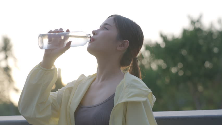 Asian women are healthy, waking up early to exercise in the park. Their favorite sports are running and yoga. They stop to drink water to refresh themselves.