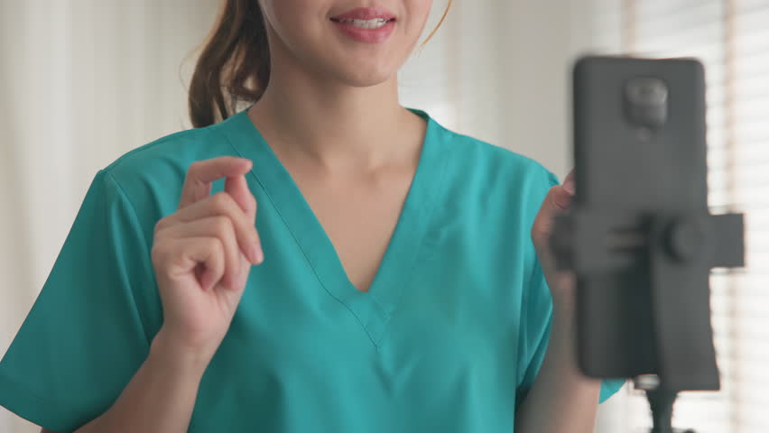 Young adult woman Gen Z asia people anti aging expert modern nurse live talk viral video selfie camera on mobile phone app mental health care. Online sharing digital virtual asian vlogger filming.