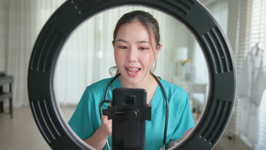 Young adult woman Gen Z asia people anti aging expert modern nurse live talk viral video selfie camera on mobile phone app mental health care. Online sharing digital virtual asian vlogger filming.