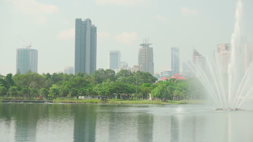 Awesome Kuala Lumpur skyline. Panning motion. The Petronas Twin Towers are reflected in water. Amazing view of scenic lake in a city park of Kuala Lumpur, Malaysia. Beautiful cityscape.