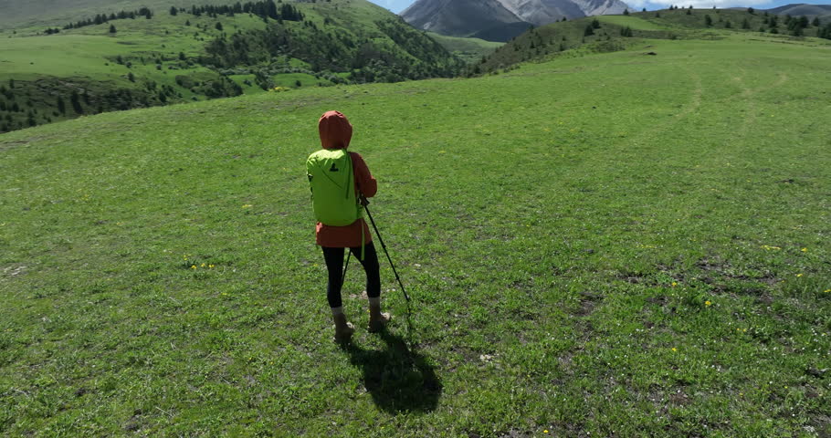 Aerial footage of woman backpacking in the beautiful flowering grassland and forest mountains,slow motion