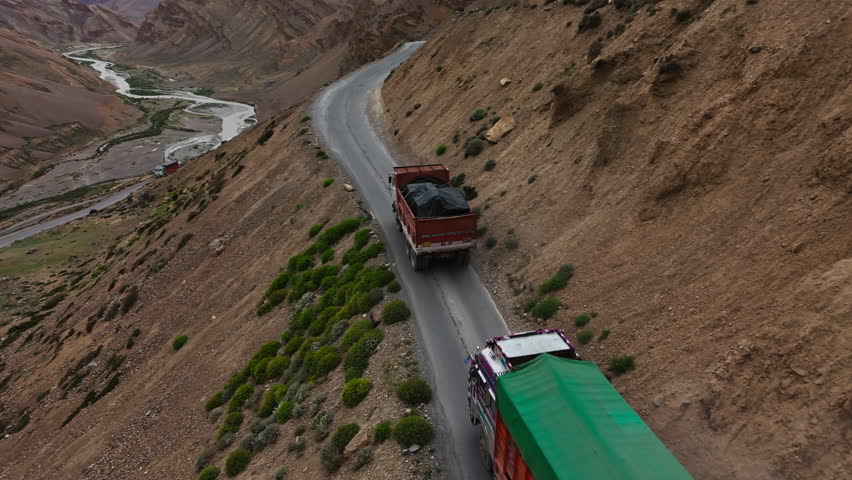 Trucks on Cliffside Road Above River Valley in Ladakh
