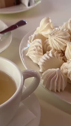 white cups of tea meringue on a plate cottage cheese casserole and cake Three chocolates three cups drink for three
