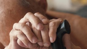 an elderly man sits holding a walking stick with his head down, emotions of old people, a grandfather with a walking stick sits thoughtfully - Powered by Shutterstock - Get 15% off with code: PIKWIZARD15