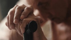 an elderly man sits holding a walking stick with his head down, emotions of old people, a grandfather with a walking stick sits thoughtfully - Powered by Shutterstock - Get 15% off with code: PIKWIZARD15