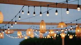 Outdoor string lights and woven rattan lamps create a warm, cozy ambiance for an evening garden party or rustic wedding setup. - Powered by Shutterstock - Get 15% off with code: PIKWIZARD15