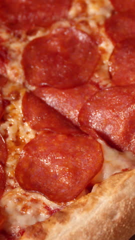 Baked pizza with melted cheese and pepperoni on golden crust viewed from top with vivid colors and rich textures, for food promo footage